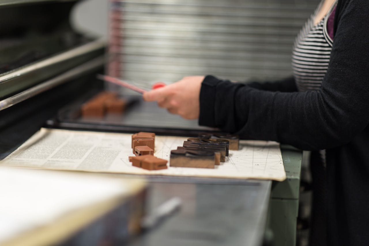 Close-up of a person working with printing blocks in a traditional manual printing workshop.